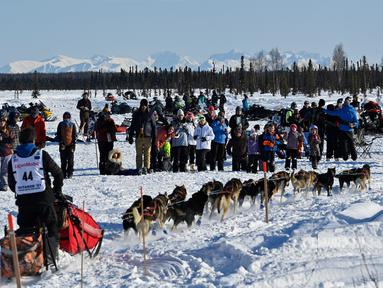 Penonton menyaksikan musher Jessie Holmes meninggalkan garis start Iditarod Sled Dog Race di Deshka Landing di Willow, Alaska, Minggu (7/3/2021). Sled Dog Trail merupakan lomba balap kereta luncur yang ditarik oleh anjing yang digelar tiap tahun. (Marc Lester/Anchorage Daily News via AP)