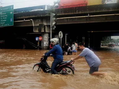 Warga membantu mendorong motor yang mogok saat berusaha menerobos banjir di Jalan Raya Kalimalang, Caman, Bekasi, Senin (20/2). Banjir setinggi 80 cm itu disebabkan drainase buruk & diperparah tingginya intensitas curah hujan (Liputan6.com/Gempur M Surya)