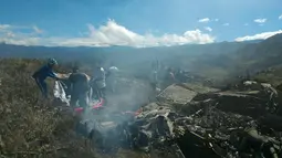Petugas dibantu relawan memeriksa kondisi pesawat Hercules TNI AU yang jatuh di kawasan Wamena, Papua, Minggu (18/12). Pesawat yang dipiloti Mayor (Pnb) Marlon Kawer itu dilaporkan jatuh dengan muatan 12 ton logistik. (HANDOUT/SEARCH AND RESCUE TEAM/AFP)