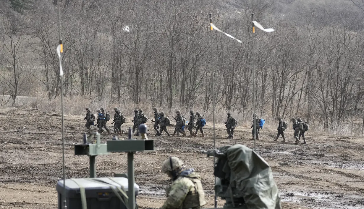 Tentara Korea Selatan berbaris ketika seorang tentara AS duduk di kendaraan militer selama latihan militer bersama di Paju, Korea Selatan, Kamis, 16 Maret 2023. (AP Photo/Lee Jin-man)