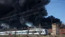 Kereta melintas di dekat perusahaan kimia Indukern yang sedang terjadi kebakaran di kawasan industri Fuente del Jarro, Paterna, Valencia, Spanyol, Rabu (8/2). (AFP PHOTO / Biel Alino)