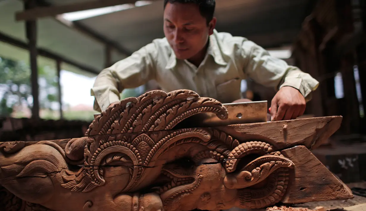 Seorang pengrajin kayu dari komunitas etnis Newar mengukir kayu di Lalitput, Nepal (19/7). Komunitas pengrajin kayu ini memperbaiki pintu dan jendela kayu yang rusak akibat gempa Nepal menjadi kayu ukiran yang menawan. (AP Photo/Niranjan Shrestha)