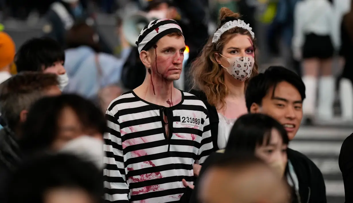 Orang-orang dengan kostum berjalan menyeberangi persimpangan jalan yang terkenal saat perayaan Halloween di distrik hiburan Shibuya, Tokyo, Jepang, 31 Oktober 2022. (AP Photo/Hiro Komae)
