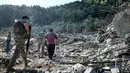 Tentara tentara Lebanon dan lainnya berjalan melewati reruntuhan bangunan yang hancur di lokasi serangan udara Israel sebelumnya di desa Aito, Lebanon utara pada 15 Oktober 2024. (JOSEPH EID/AFP)