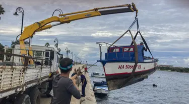 Pekerja memindahkan perahu dari air di teluk Havana, Kuba, Senin, 26 September 2022. Badai Ian semakin kuat saat mendekati ujung barat Kuba di jalur untuk menghantam pantai barat Florida sebagai badai besar paling cepat pada hari Rabu. (Foto AP/Milexsy Duran)