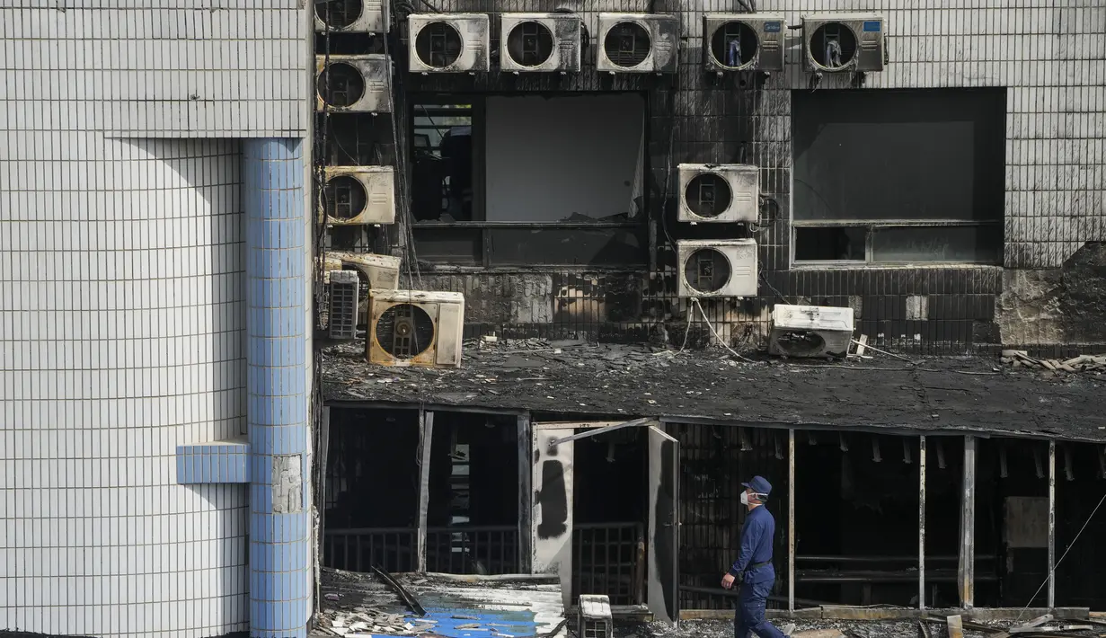Bagian luar gedung menghitam dan hangus di beberapa tempat, serta mobil polisi terlihat diparkir di pintu masuk utara. (AP Photo/Andy Wong)