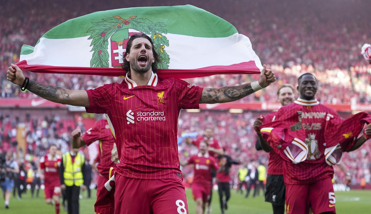 Pemain Liverpool, Dominik Szoboszlai melakukan selebrasi dengan membawa bendera Hungaria setelah membawa timnya memastikan gelar juara Liga Inggris 2024/2025 di Anfield, Liverpool, Inggris, Minggu (27/04/2025) waktu setempat. (AP Photo/Jon Super)