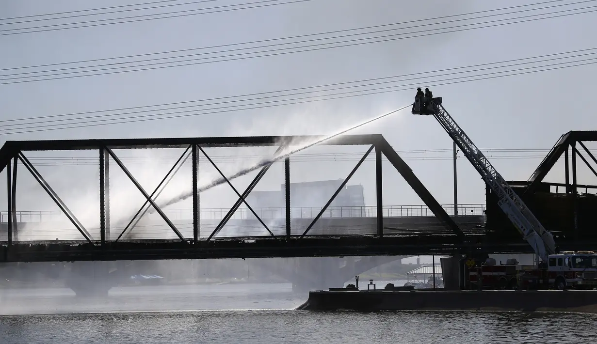 Petugas pemadam kebakaran berupaya memadamkan api saat kereta barang tergelincir dan terbakar di jembatan Danau Kota Tempe, Arizona, Amerika Serikat, Rabu (29/7/2020). Ratusan petugas pemadam kebakaran, polisi, dan paramedis dikerahkan langsung ke lokasi kejadian. (AP Photo/Ross D. Franklin)