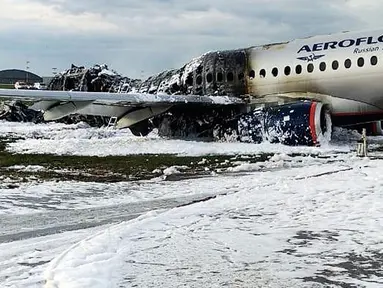 Pesawat Sukhoi Superjet-100 milik maskapai Aeroflot dikelilingi oleh busa dari pemadam kebakaran setelah melakukan pendaratan darurat dan terbakar di Bandara Sheremetyevo, Moskow, Rusia, Minggu (5/5/2019). Sedikitnya 41 orang tewas dalam kecelakaan pesawat itu. (Moscow News Agency photo via AP)