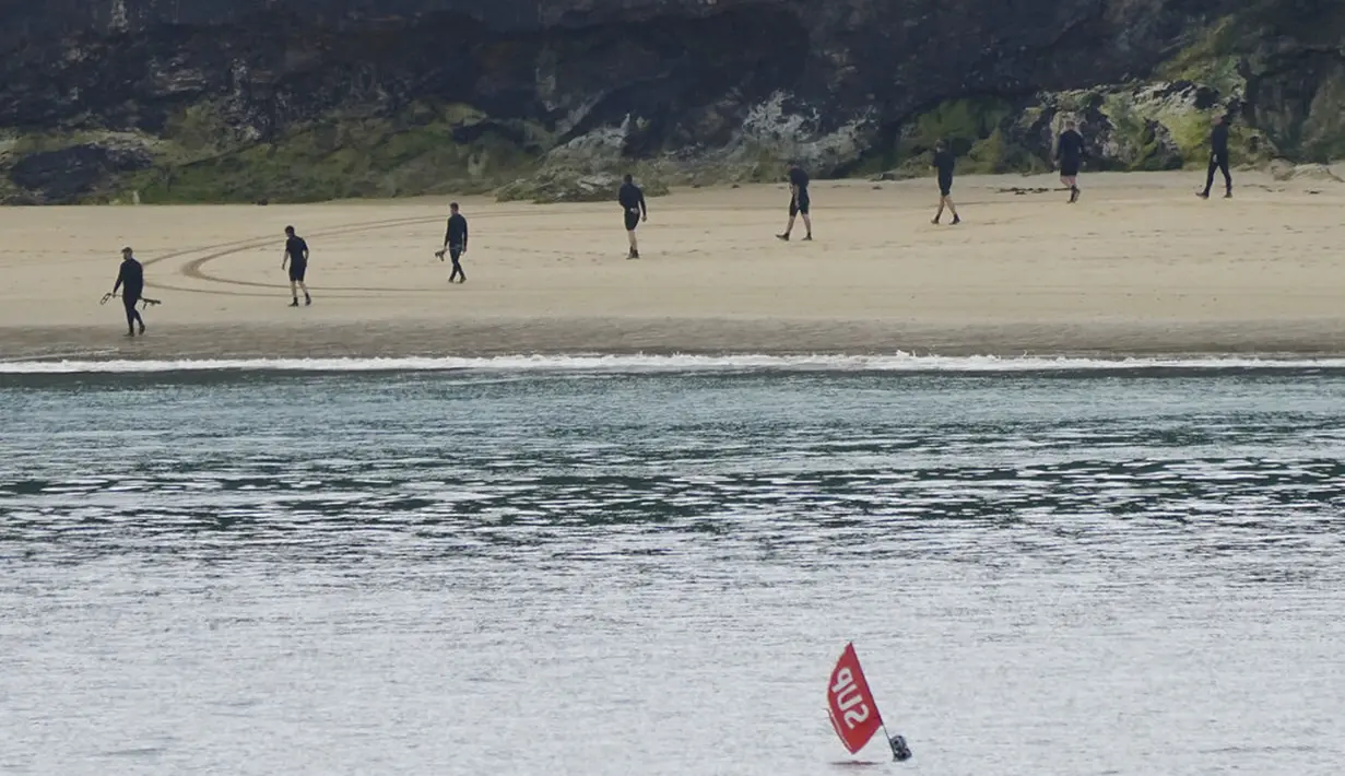 Polisi menggeledah pantai dengan detektor logam jelang KTT G7 di Carbis Bay, Cornwall, Inggris, Senin (7/6/2021). Ribuan polisi tambahan mulai berdatangan di Devon dan Cornwall menjelang KTT G7 pada 11-13 Juni. (Aaron Chown/PA via AP)