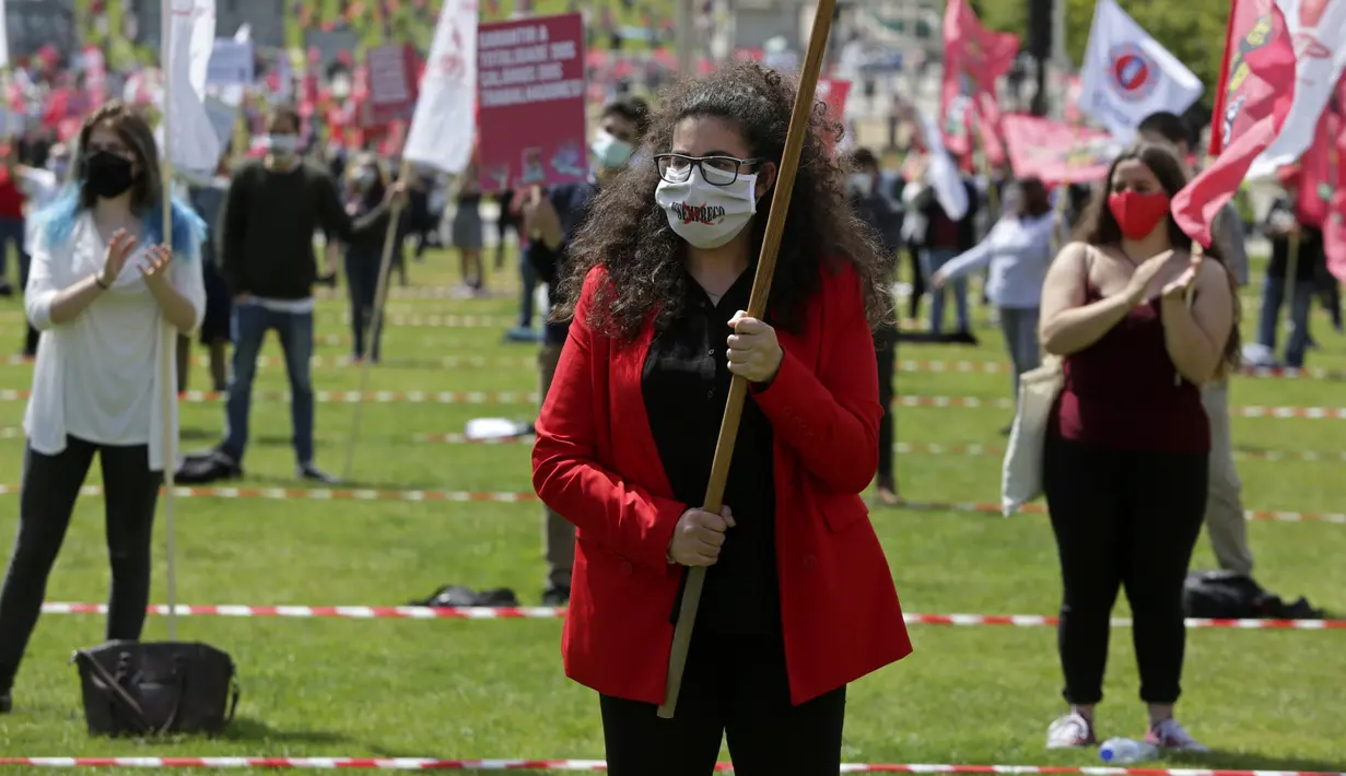 Delegasi serikat pekerja mengenakan masker sambil membawa bendera saat memperingati Hari Buruh di tengah pandemi COVID-19 di Lisbon, Portugal, Jumat (1/5/2020). Aksi ini sudah mendapat persetujuan Kementerian Kesehatan dan Dalam Negeri Portugal. (AP Photo/Armando Franca)