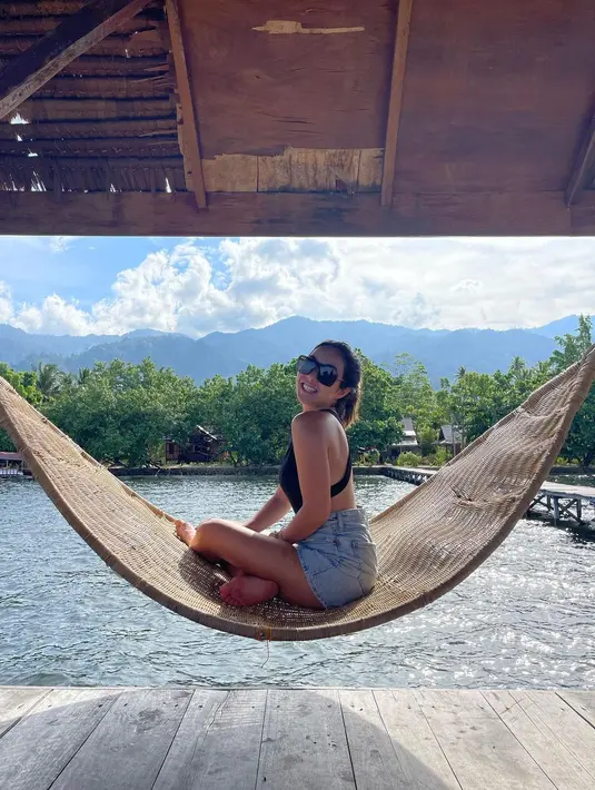 Menikmati indahnya di pantai, Gisella Anastasia duduk di atas hammock dengan pakaian santai. Ia mengenakan bikini hitam dan jeans short pants. Foto ini sempat viral di media sosial hingga menjadi trending. (instagram/gisel_la)
