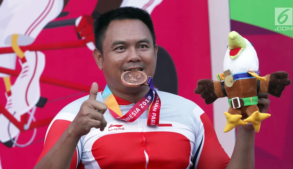 Atlet ParaCycling, Soemantri menggigit medali perunggu nomor Mens H4-5 Individual Time Trial Road Race Asian Para Games 2018 di Sirkuit Sentul, Bogor, Senin (8/10). Soemantri berhasil merebut medali perunggu. (Liputan6.com/Helmi Fithriansyah)
