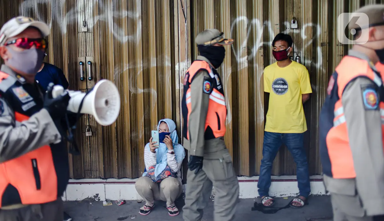 Petugas Satpol PP melakukan sosialisasi saat menertibkan pedagang yang nekat berjualan selama masa pandemi COVID-19 di kawasan Pasar Tanah Abang, Jakarta, Jumat (22/5/2020). Gubernur DKI Jakarta Anies Baswedan menambah PSBB selama 14 hari mulai tanggal 22 Mei 2020. (Liputan6.com/Faizal Fanani)