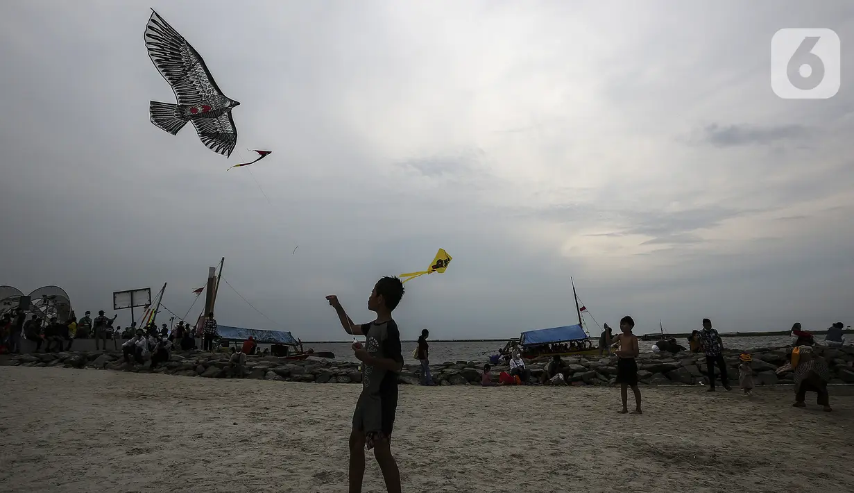 Pengunjung bermain layangan di Pantai Karnaval Ancol, Jakarta, Jumat (14/5/2021). Ancol dibuka khusus bagi warga ber-KTP DKI Jakarta dan membatasi jumlah wisatawan dengan kapasitas 30 persen. (Liputan6.com/Johan Tallo)