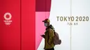 Seorang pria mengenakan masker pelindung berjalan di terowongan sebuah stasiun metro di Tokyo, Jepang, 11 Maret 2020. Pandemi virus corona COVID-19 membuat Jepang dilema untuk tetap menggelar Olimpiade 2020. (Photo by Philip FONG/AFP)