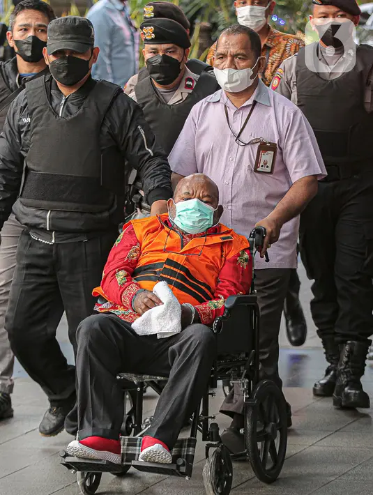 Tersangka kasus dugaan korupsi pembangunan infrastruktur di Provinsi Papua Lukas Enembe  Lukas Enembe dibawa dari RSPAD Gatot Subroto untuk menjalani pemeriksaan di Gedung Merah Putih KPK, Jakarta, Kamis (12/1/2023). Lukas yang masih mengenakan rompi oranye dan tangannya diborgol turun dari mobil KPK dan langsung menggunakan kursi roda. (Liputan6.com/Faizal Fanani)