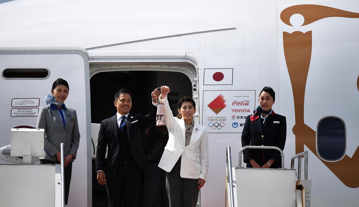 Atlet peraih tiga kali medali emas olimpiade, Tadahiro Nomura dan Saori Yoshida, membawa api untuk obor Olimpiade Tokyo 2020 saat tiba dari Yunani di Pangkalan Udara Matsushima, Jepang, Jumat (20/3).Di tengah pandemi virus corona Covid-19, prosesi menuju Olimpiade Tokyo 2020. (AFP/Philip Fong)