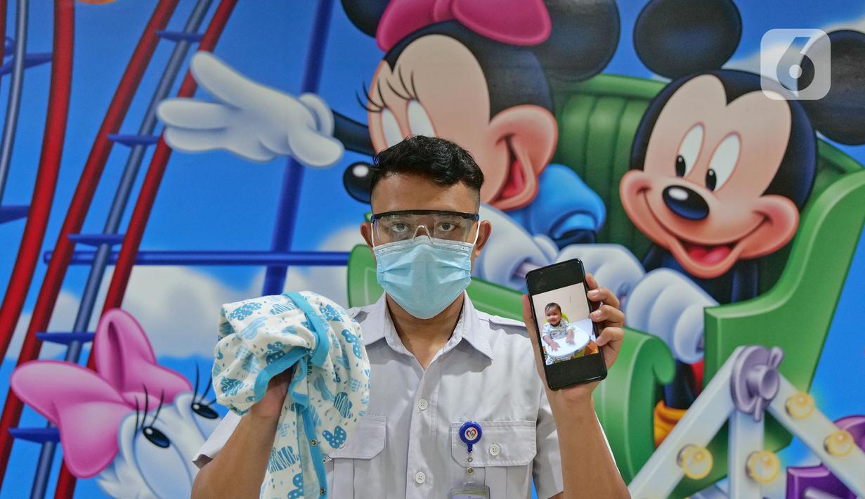 Petugas farmasi Oddy Sutanto menunjukkan foto anaknya saat di RSUD Pasar Minggu, Jakarta, Jumat (22/5/2020). Oddy Sutanto sudah 2 bulan tidak bertemu keluarga selama bertugas menjaga COVID -19 di RSUD Pasar Minggu. (Liputan6.com/Herman Zakharia)