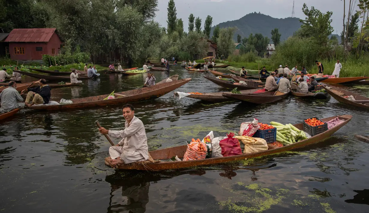 Seorang pria Kashmir mendayung perahunya dengan membawa sayur-sayuran untuk dijual di pasar terapung di Danau Dal di Srinagar, Kashmir yang dikuasai India pada 26 Juli 2020. Sayuran yang diperdagangkan di pasar terapung ini disuplai ke Srinagar dan banyak kota di lembah Kashmir. (AP Photo/Dar Yasin)