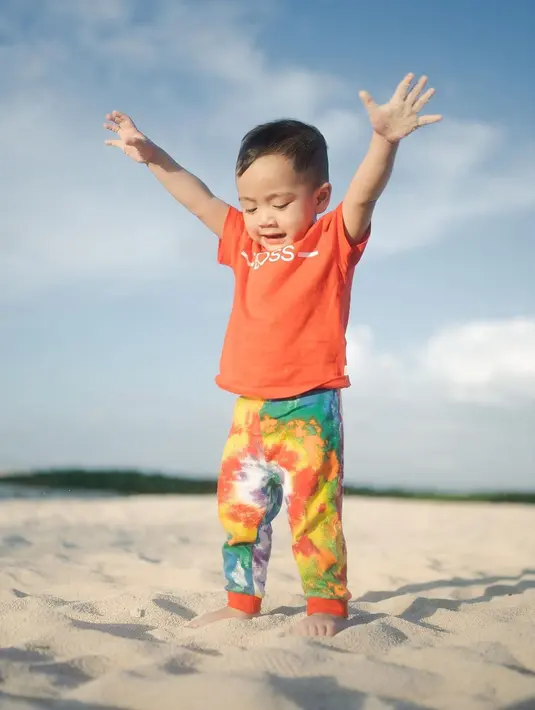 Bermain di pantai, Cipung mengenakan outfit colorful. Ia mengenakan atasan kaus oranye dengan celana panjang tie-dye yang bernuansa senada. Foto: Instagram.