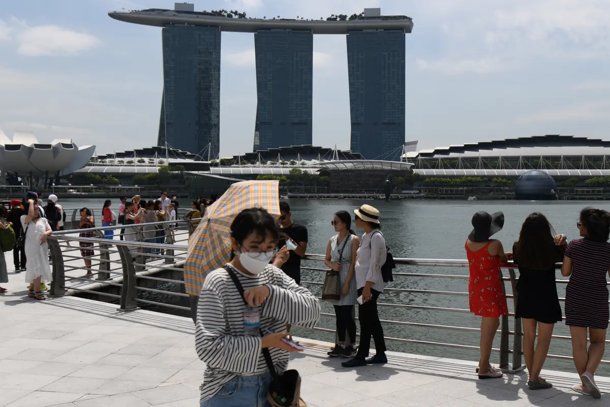Seorang pengunjung, yang mengenakan masker pelindung di tengah kekhawatiran tentang penyebaran Virus Corona COVID-19, berjalan di sepanjang Merlion Park di Singapura pada 17 Februari 2020. (Roslan RAHMAN / AFP)
