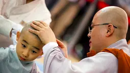 Seorang biksu Budha mencukur kepala seorang biksu pemula saat upacara pemberkatan Biksu di kuil Jogye, Seoul, Senin (11/5/2015). Sepuluh orang anak diberikan kesempatan untuk mengalami kehidupan sebagai biksu selama dua minggu. (REUTERS/Thomas Peter)