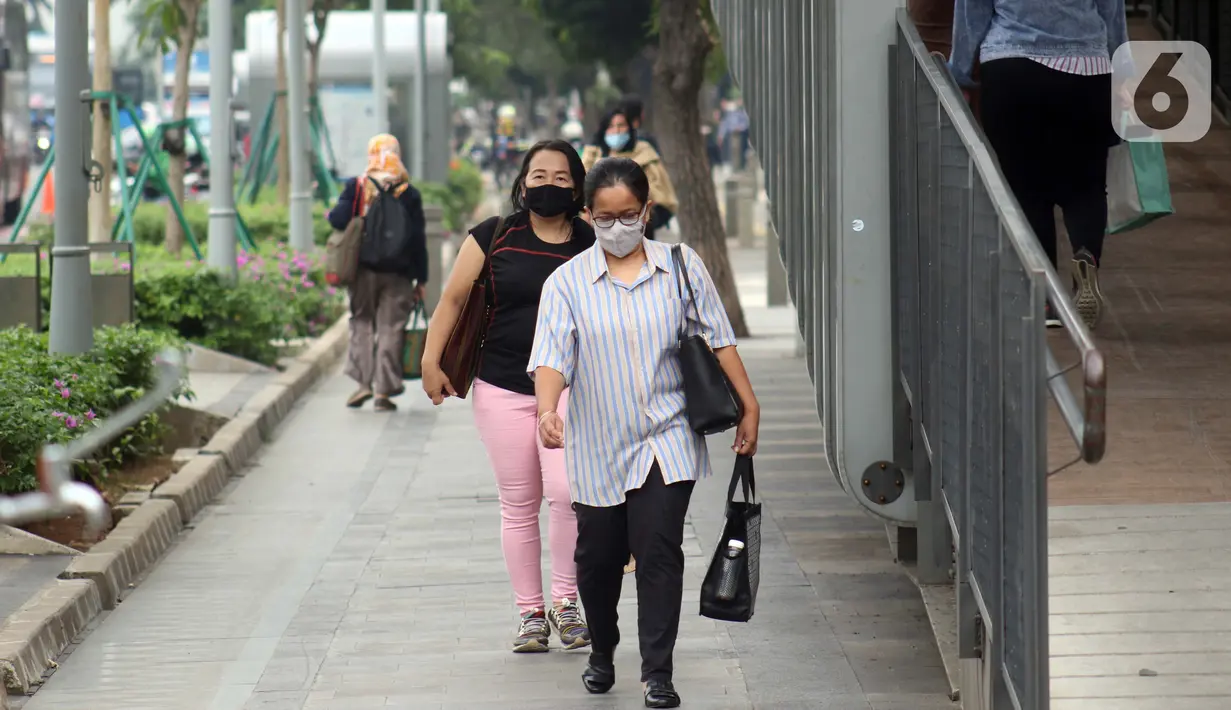 Warga mengenakan masker melintas di trotoar Jalan Jenderal Sudirman, Jakarta, Kamis (9/7/2020). Berdasar data yang diumumkan pemerintah pada Kamis (9/7) ada penambahan 2.657 orang yang terinfeksi COVID-19 sehingga jumlah penderita menjadi 70.736. (Liputan6.com/Helmi Fithriansyah)