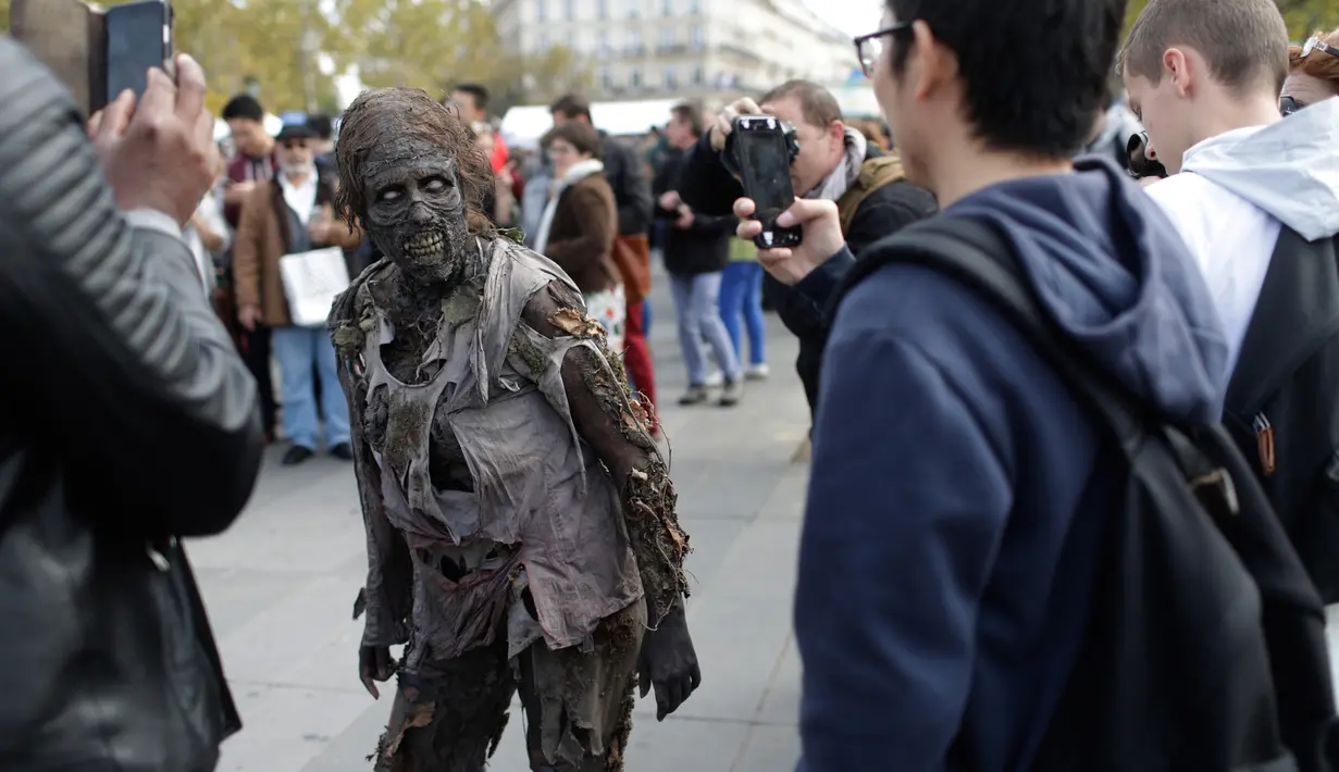 Seorang peserta mengenakan kostum zombie berpose saat mengikuti "Zombie Walk" di Paris, Prancis (7/10). Acara ini diadakan setiap tahun dan manjadi daya tarik untuk wisatawan. (AFP Photo/Thomas Samson)