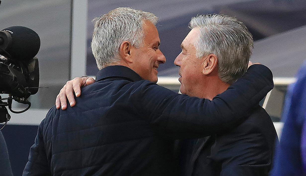 Pelatih Tottenham Hotspur, Jose Mourinho, berpelukan dengan pelatih Everton, Carlo Ancelotti, pada laga Premier League, Senin (6/7/2020). Mourinho rela langgar aturan jarak sosial demi memeluk Carlo Ancelotti yang merupakan idolanya. (AFP/Adam Davy)