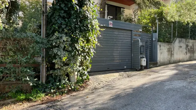 Pintu garasi rumah seorang diplomat senior Italia di pinggiran kota Athena, Yunani ditutup menyusul serangan yang menghancurkan sebuah mobil dan merusak yang kedua. (Lefteris Pitarakis/AP)