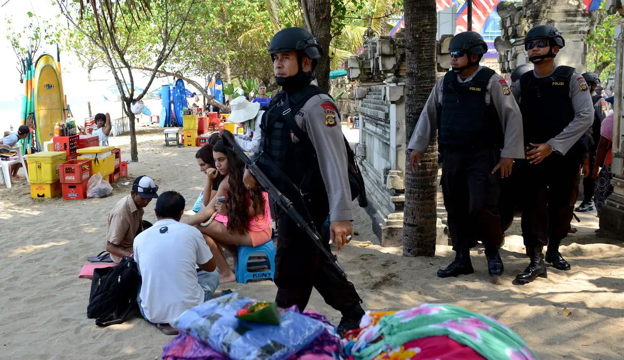 Petugas Brimob dengan senjata laras panjang dan rompi antipeluru menyebar di Pantai Kuta, Denpasar, Rabu (20/1). Polisi Indonesia mengumumkan bahwa mereka telah menangkap seorang pria yang membiayai serangan Jakarta mematikan. (AFP PHOTO/SONNY TUMBELAKA)
