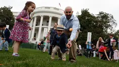 Seorang pria membantu anaknya menggelindingkan telur saat lomba perayaan Paskah di halaman Gedung Putih, Washington, Senin (17/4).Lomba yang diselenggarakan setiap tahunnya ini merupakan lomba menggelindingkan telur yang ke-139. (AP Photo/Carolyn Kaster)