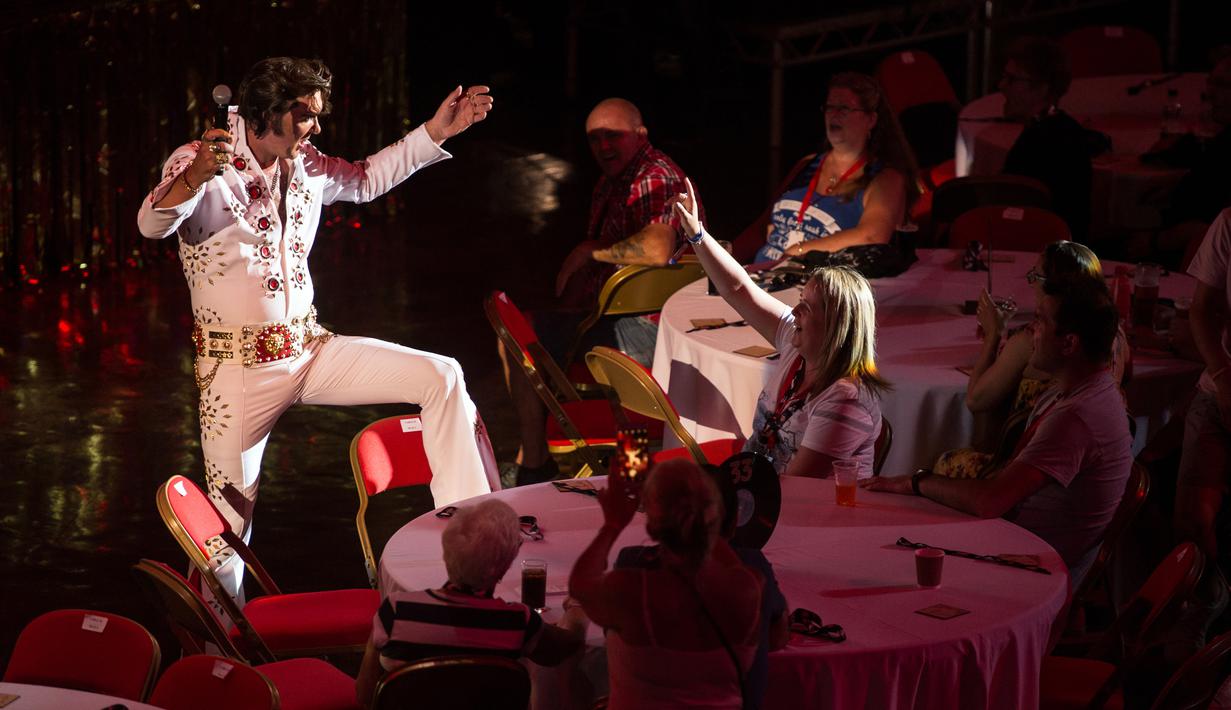 Penyanyi Jason Dale berinteraksi dengan penonton saat tampil dalam pembukaan 'Perayaan Elvis 2018' di Blackpool Winter Gardens, Barat Laut Inggris, Jumat (29/6). Peringatan Elvis Presley ini dihadiri artis, pedagang, dan para penggemar. (Oli SCARFF/AFP)