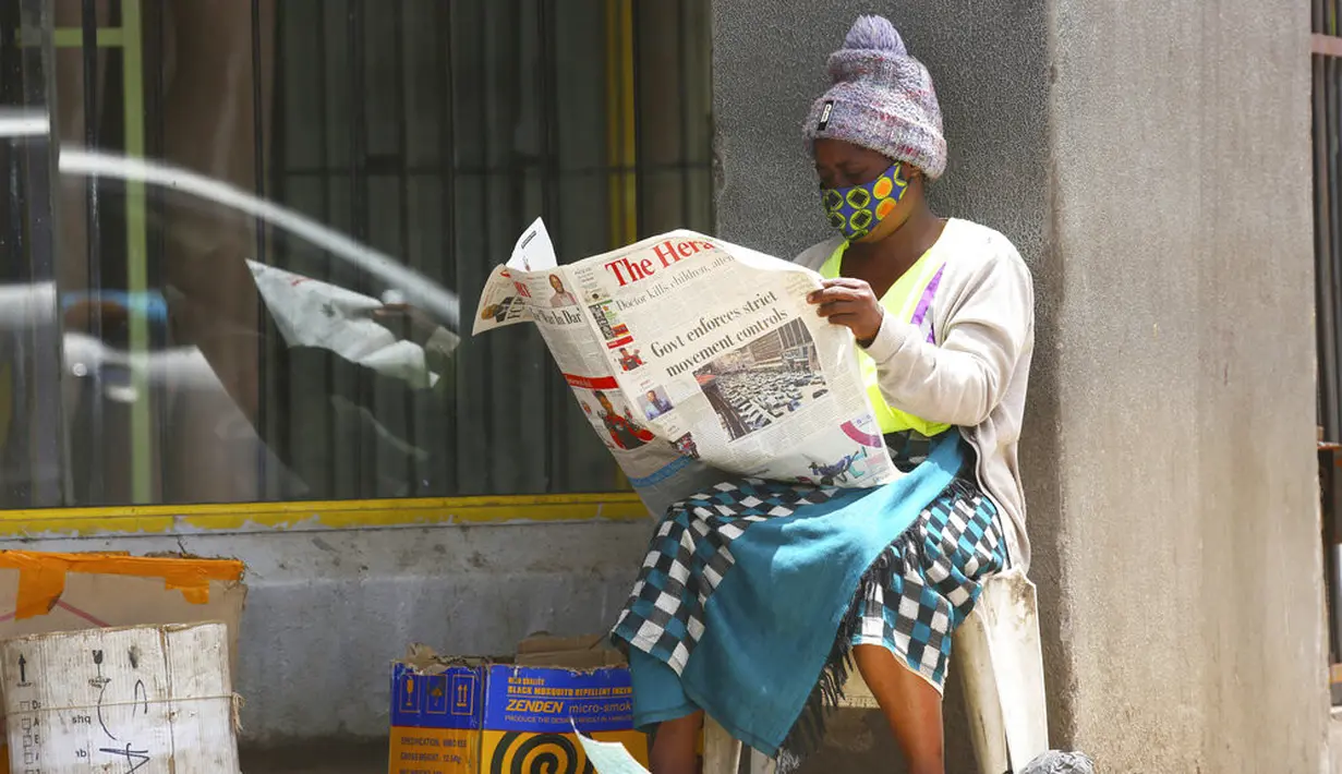 Seorang pedagang membaca koran saat menunggu pembeli di Harare, Zimbabwe, Selasa (5/1/2021). Menanggapi meningkatnya infeksi COVID-19, Zimbabwe telah memberlakukan kembali jam malam, melarang pertemuan publik, dan menangguhkan pembukaan sekolah tanpa batas waktu. (AP Photo/Tsvangirayi Mukwazhi)
