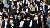 Para penumpang yang memakai masker wajah untuk melindungi dari penyebaran virus corona berjalan di sebuah jalan di Tokyo, 17 November 2020. (Foto: AP / Koji Sasahara)