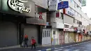 Warga Palestina berjalan melewati toko-toko yang tutup di kota Nablus, Tepi Barat, (7/12). Usai Presiden AS, Donald Trump mengumumkan Yerusalem sebagai ibu kota Israel suasana sepi terlihat di kawasan tersebut. (AFP Photo/Hazem Bader)