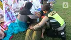 Anggota polisi dari Polda Bali membantu warga yang pingsan saat melakukan shalat Idul Fitri di Lapangan Pegok, Sesetan, Denpasar, Sabtu (22/4/2023). (merdeka.com/Arie Basuki)