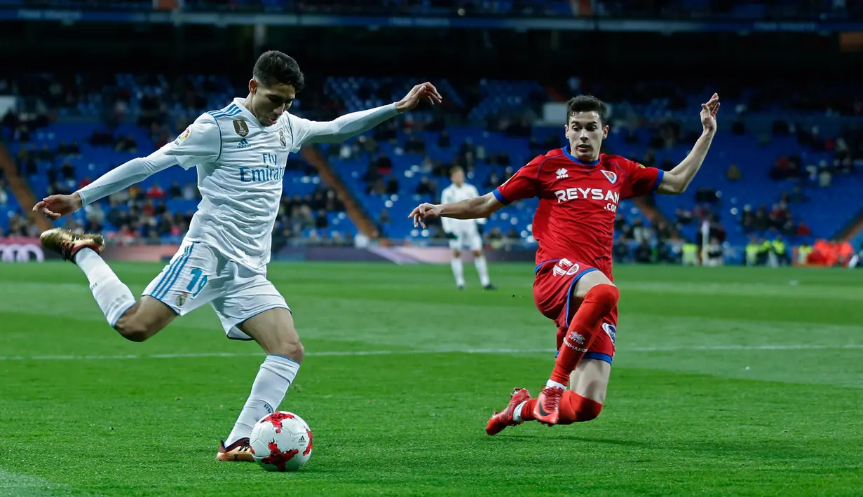 Pemain Real Madrid, Achraf Hakimi melakukan tendangan di samping pemain Numancia, Nacho Sanchez pada leg kedua babak 16 besar Copa del Rey di Santiago Bernabeu, Kamis (11/1). Real Madrid harus puas dengan hasil imbang 2-2. (AP/Francisco Seco)