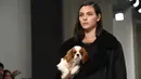 Seorang model menggendong anak anjing saat memamerkan rancangan Tod's di Milan Fashion Week, Milan, Italia, Jumat (23/2). Selain Gigi Hadid, model Tod's lainnya juga membawa anak anjing saat tampil di Milan Fashion Week. (Filippo MONTEFORTE/AFP)