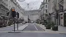 Suasana jalan ke arah Piccadilly Circus, di pusat kota London yang kosong pada Hari Natal, Sabtu (25/12/2021). Dari Bethlehem dan Frankfurt ke London dan Boston, gelombang virus corona varian omicron meredam Malam Natal untuk tahun kedua. (Jonathan Brady/PA via AP)