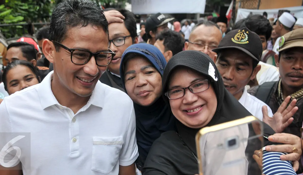 Cawagub DKI Jakarta, Sandiaga Uno foto bersama warga saat sosialisasi kampanye di Petojo Binatu, Jakarta Pusat, Jumat (17/3). Selain meminta dukungan dan doa, Sandiaga memaparkan program KJP Plus ke warga bila terpilih nanti. (Liputan6.com/Yoppy Renato)