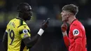 Pemain Watford Moussa Sissoko (kiri) dan pemain Norwich City Brandon Williams adu argumen pada pertandingan sepak bola Liga Inggris di Vicarage Road Stadium, Watford, Inggris, Sabtu (22/1/2022). Norwich City menang 3-0. (Adrian DENNIS/AFP)