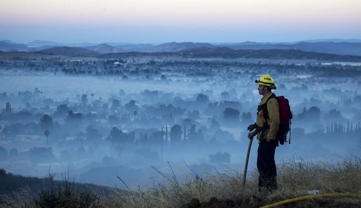 Petugas melihat kebakaran hutan di Cherry Valley, California (1/8/2020). Menurut Departemen Pemadam Kebakaran Wilayah dan Departemen Kehutanan dan Perlindungan Kebakaran California (Cal Fire), api telah meluas sejak Jumat (31/7) malam menjadi 4.125 hektar. (AP Photo/Ringo H.W. Chiu)