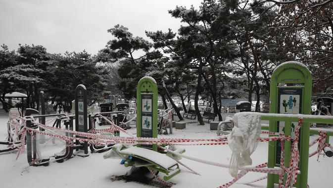 Perlengkapan fitness yang tertutup salju direkam untuk tindakan social distancing sebagai pencegahan terhadap virus corona di Goyang, Korea Selatan, Kamis (28/1/2021). (AP/Lee Jin-man)