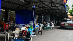 Pasien yang terduga Covid-19 beristirahat di tempat parkir yang diubah menjadi bangsal di luar rumah sakit di kota Binan, provinsi Laguna, Manila, di tengah rekor infeksi yang dipicu oleh varian Delta yang sangat menular pada Senin (6/9/2021). (Photo by Maria Tan / AFP)