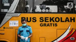 Petugas berjaga di depan bus sekolah yang terparkir di Kawasan Stasiun Sudirman, Jakarta, Jumat (19/6/2020). Dishub DKI Jakarta telah mengerahkan 50 armada bus sekolah untuk membantu mengurai lonjakan penumpang KRL. (Liputan6.com/Faizal Fanani)
