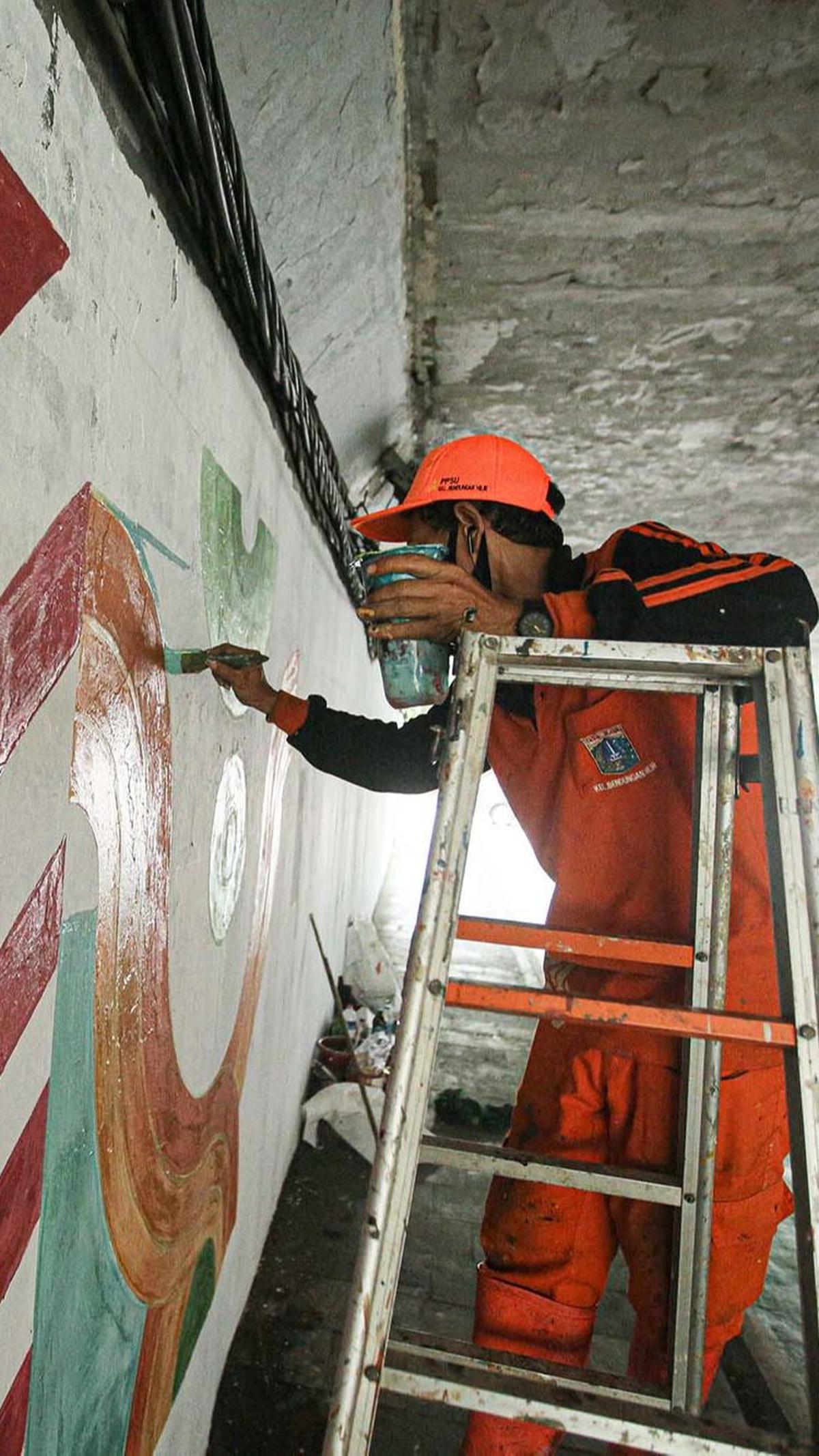Pasukan oranye sampai menaiki tangga saat menggoreskan kuasnya pada tembok kolong Semanggi.