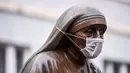 Masker terpasang pada wajah patung Bunda Teresa di Pristina, Kosovo, Kamis (19/12/2019). Selama beberapa bulan terakhir, Pristina terdaftar sebagai salah satu kota dengan kualitas udara terburuk di dunia. (Armend NIMANI/AFP)