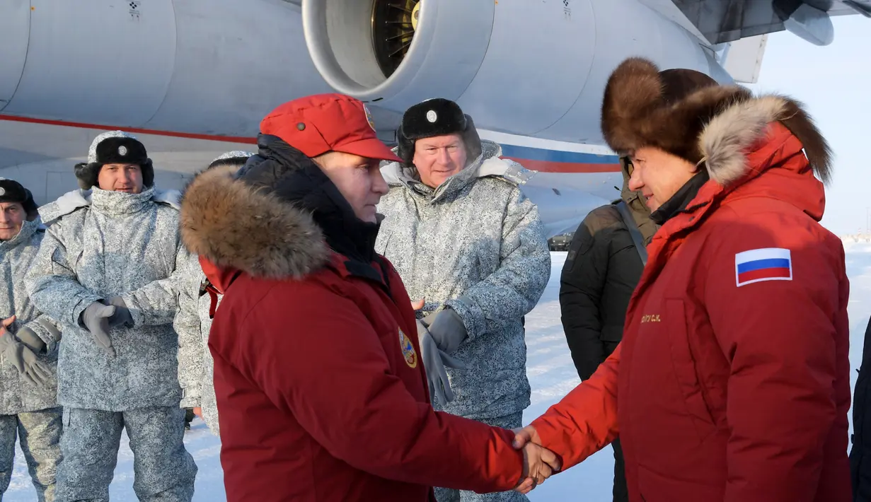 Presiden Rusia, Vladimir Putin berjabat tangan dengan Menteri Pertahanan Sergei Shoigu, saat mengunjungi Franz Josef Land di Arctic, Rusia, (29/3). (Alexei Druzhinin, Sputnik, Kremlin Pool Photo via AP)